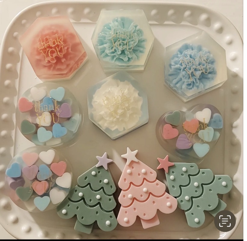 Pastel floral, heart and Christmas tree soaps arranged on a white tray